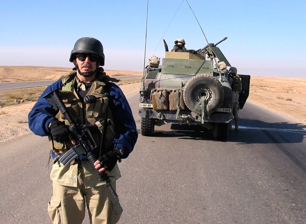 Author on the road to Mosul, 2005 armed with a Bushmaster SBR and a Glock 17. Note the Mk 19 grenade launcher on the HUMVEE.